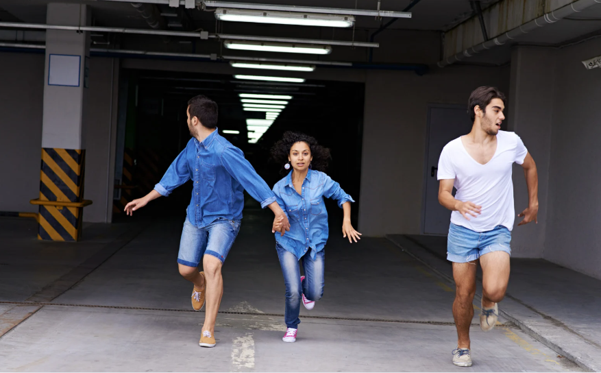 A group of people are running through a parking garage holding hands.