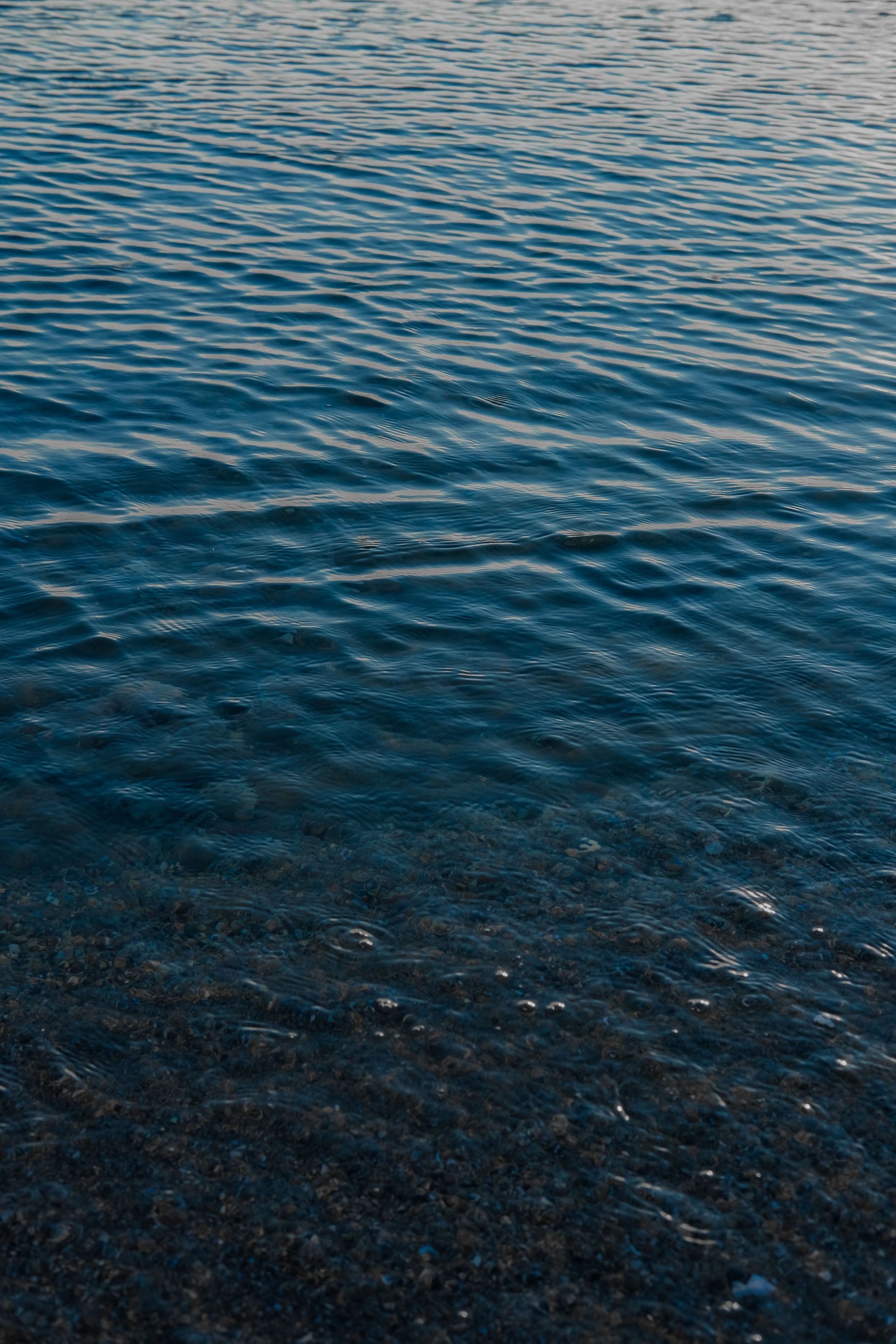 Rimpelend blauw water met zachte golven en glinsterende weerspiegelingen