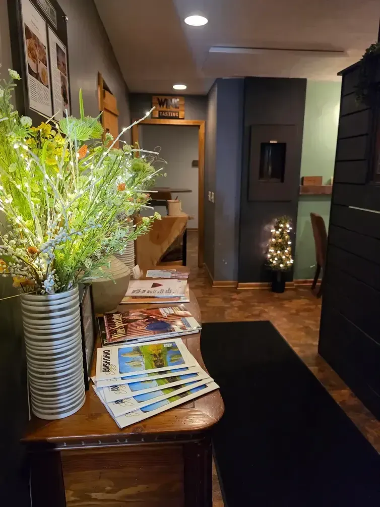Reception area with wooden counter, magazines, flowers, and a black floor runner in a dim hallway