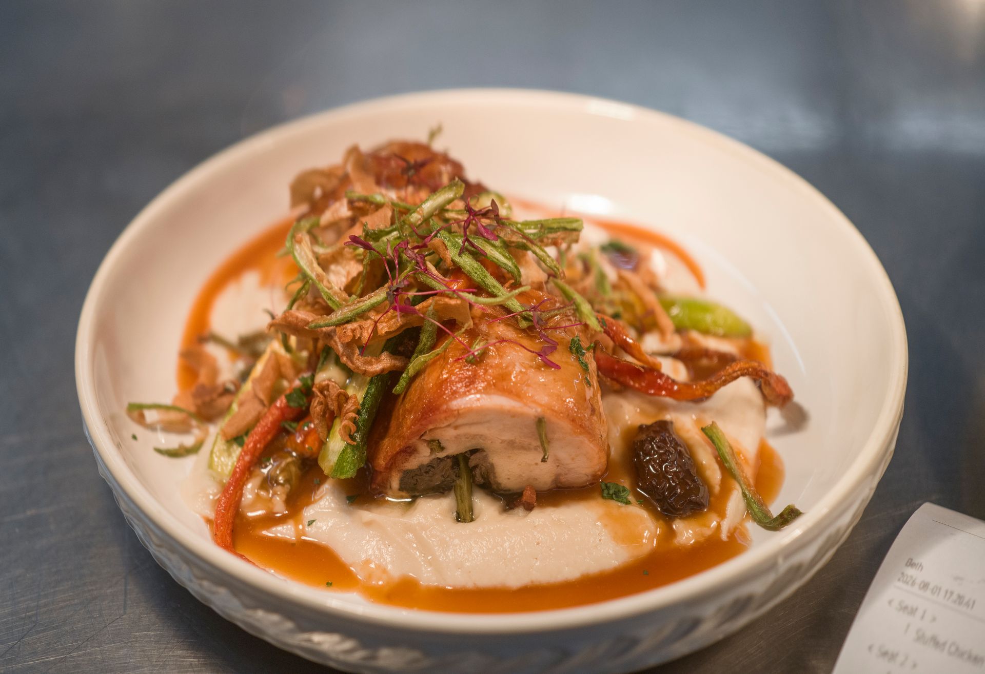 Plated fish dish topped with herbs and sauce in a white bowl on a table