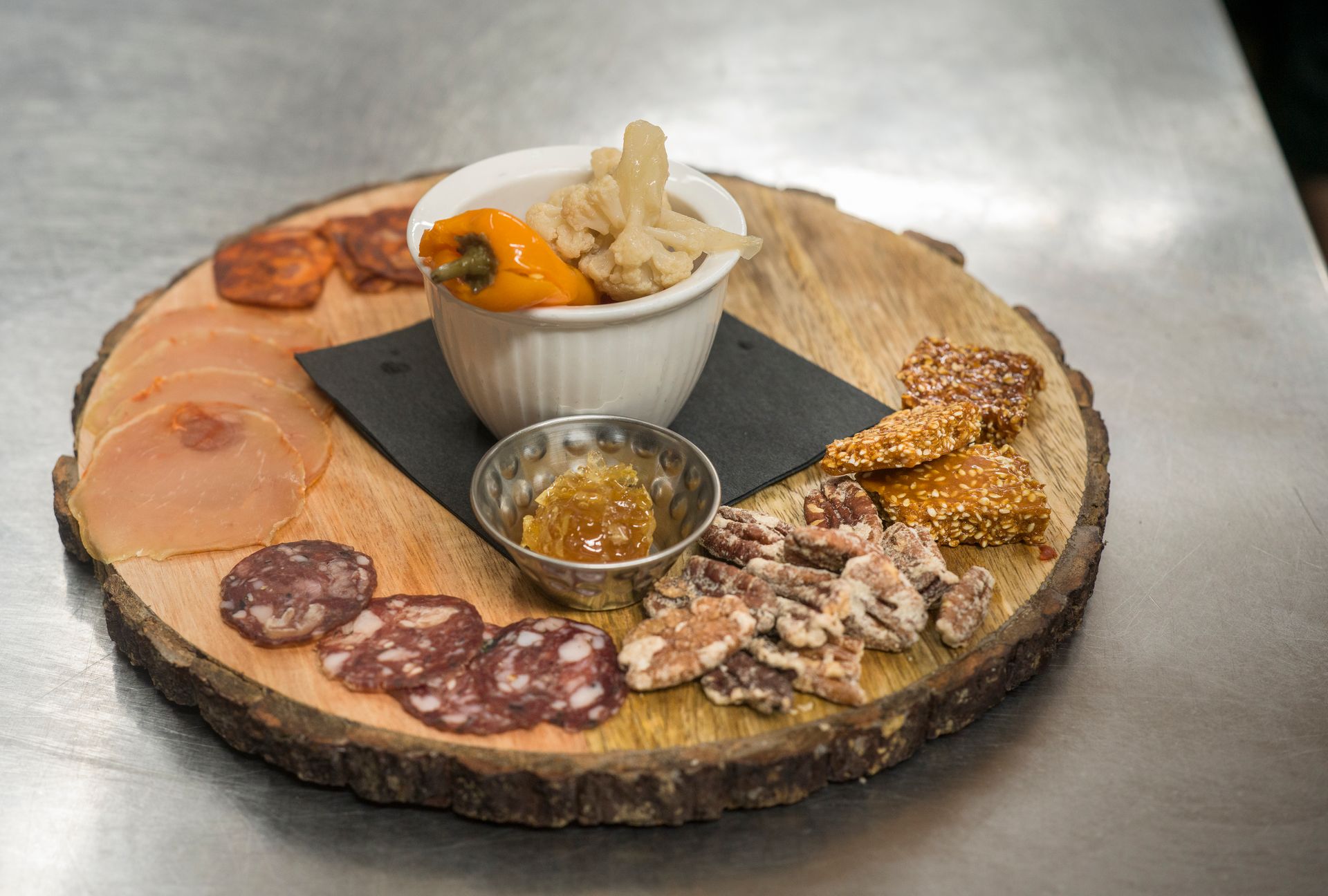 Charcuterie board with sliced meats, cheese, crackers, and spreads on a wooden slab