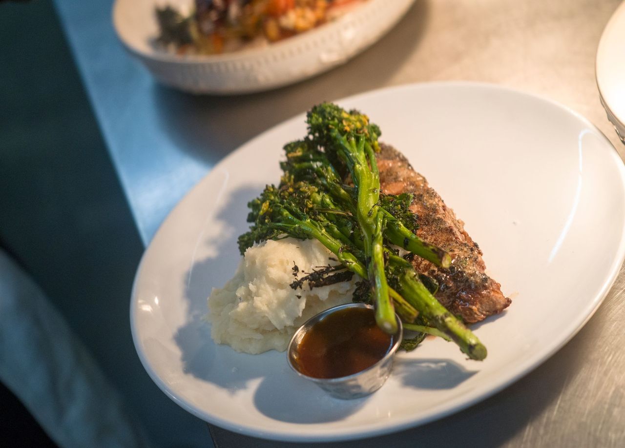 Plated broccolini and rice with sauce on a white dish in a restaurant setting