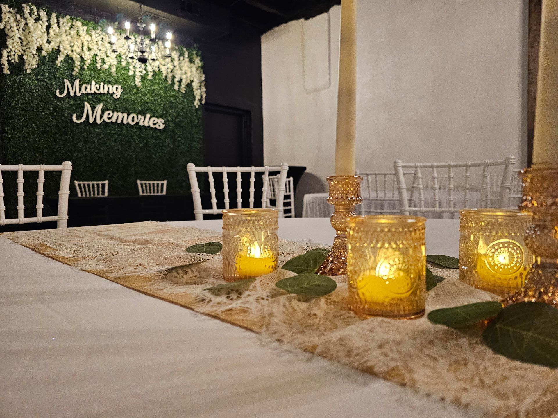 A table setting with tea light candles on a lace runner, facing a