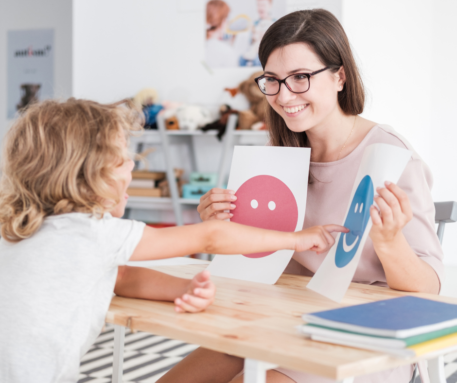 A woman is giving a child a picture of a smiley face.