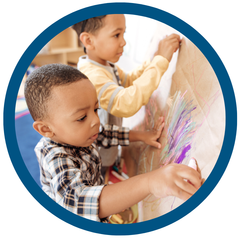 Two young boys are drawing on a wall with markers.