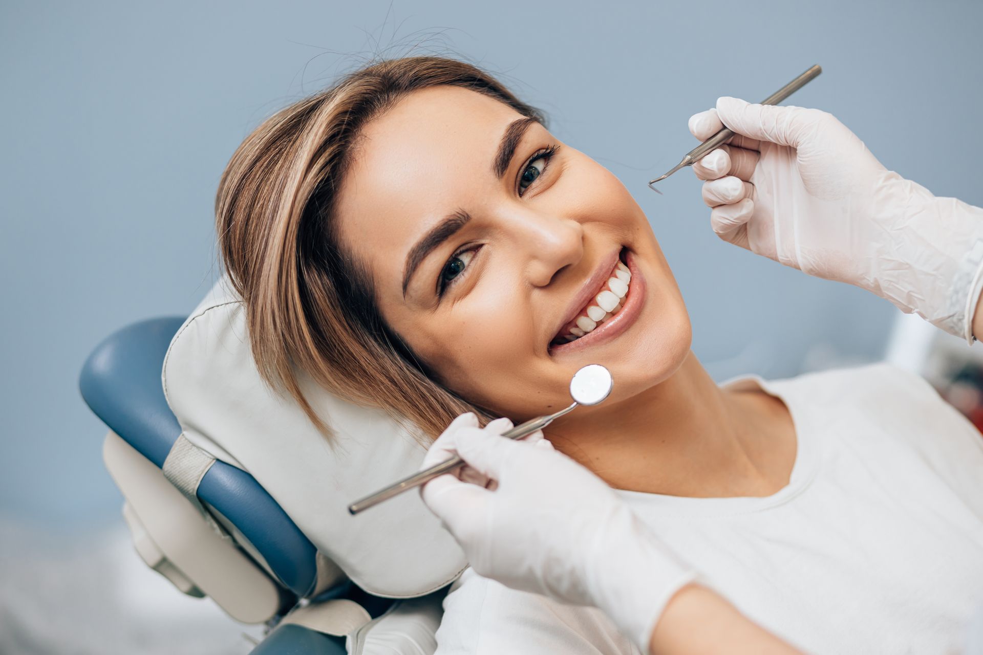 View of a woman being serviced by a dentist, smiling at the camera.
