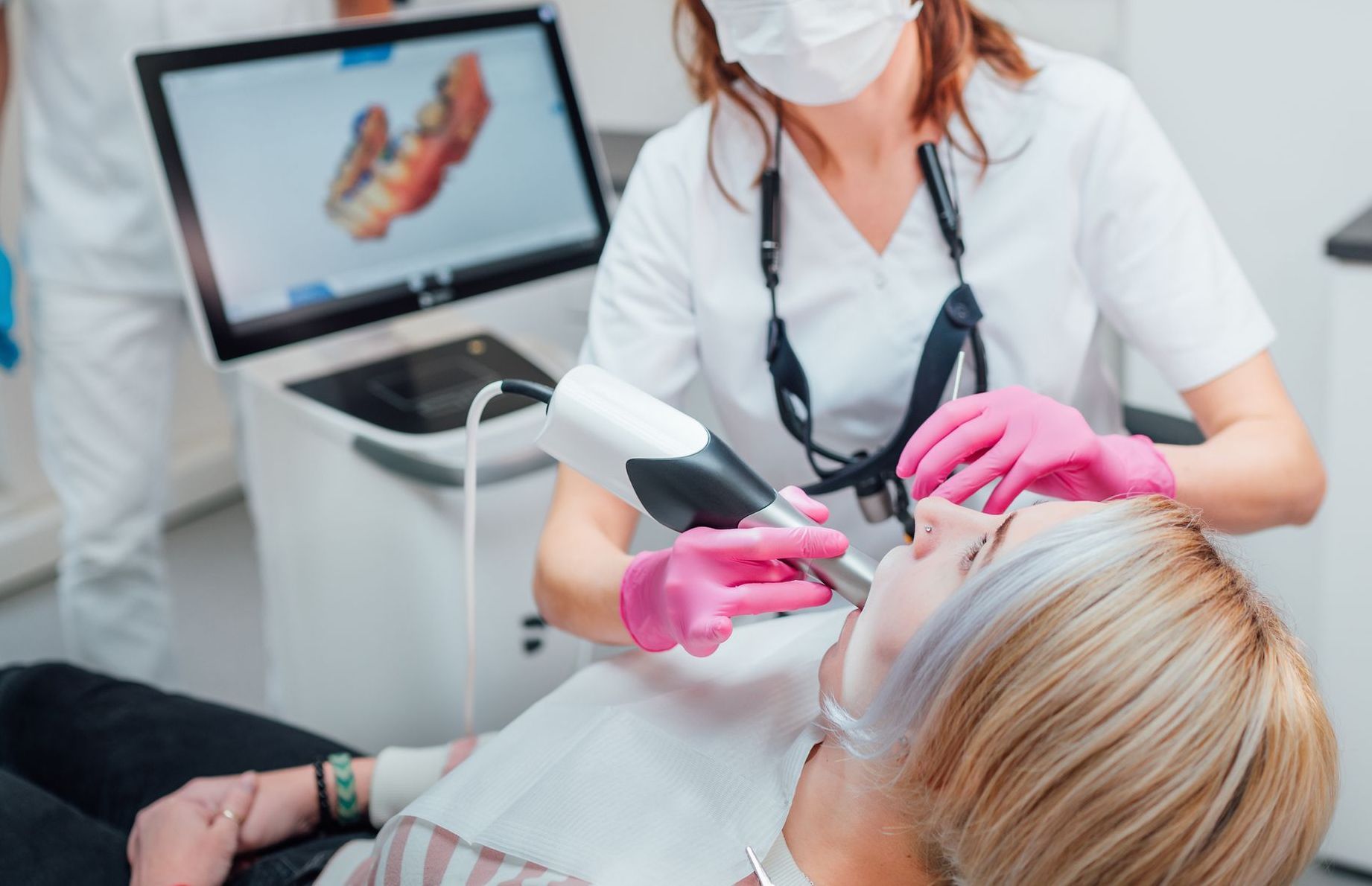 A dentist is holding a clear brace in front of a patient.