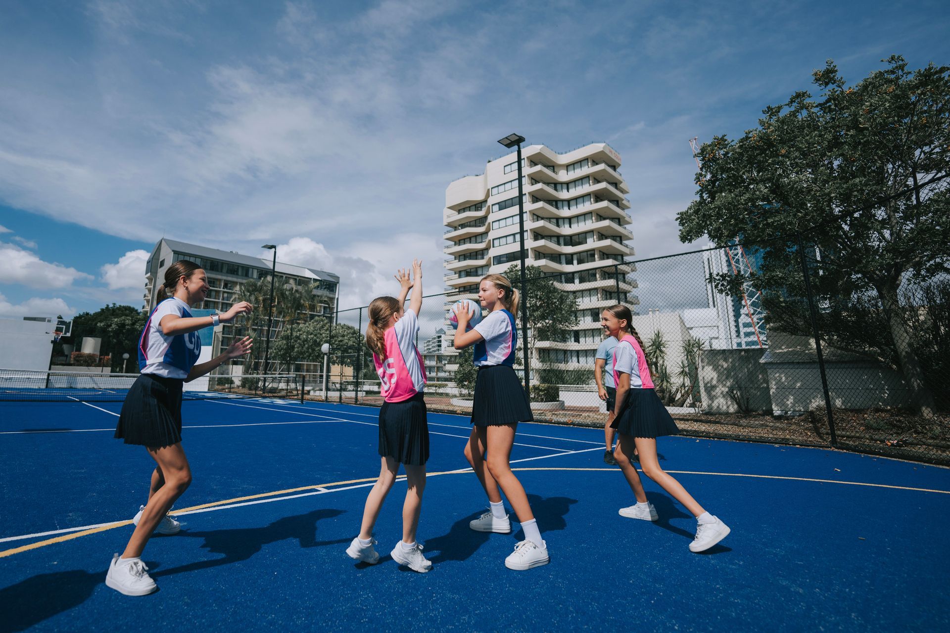 A group of young girls are playing netball on a court.