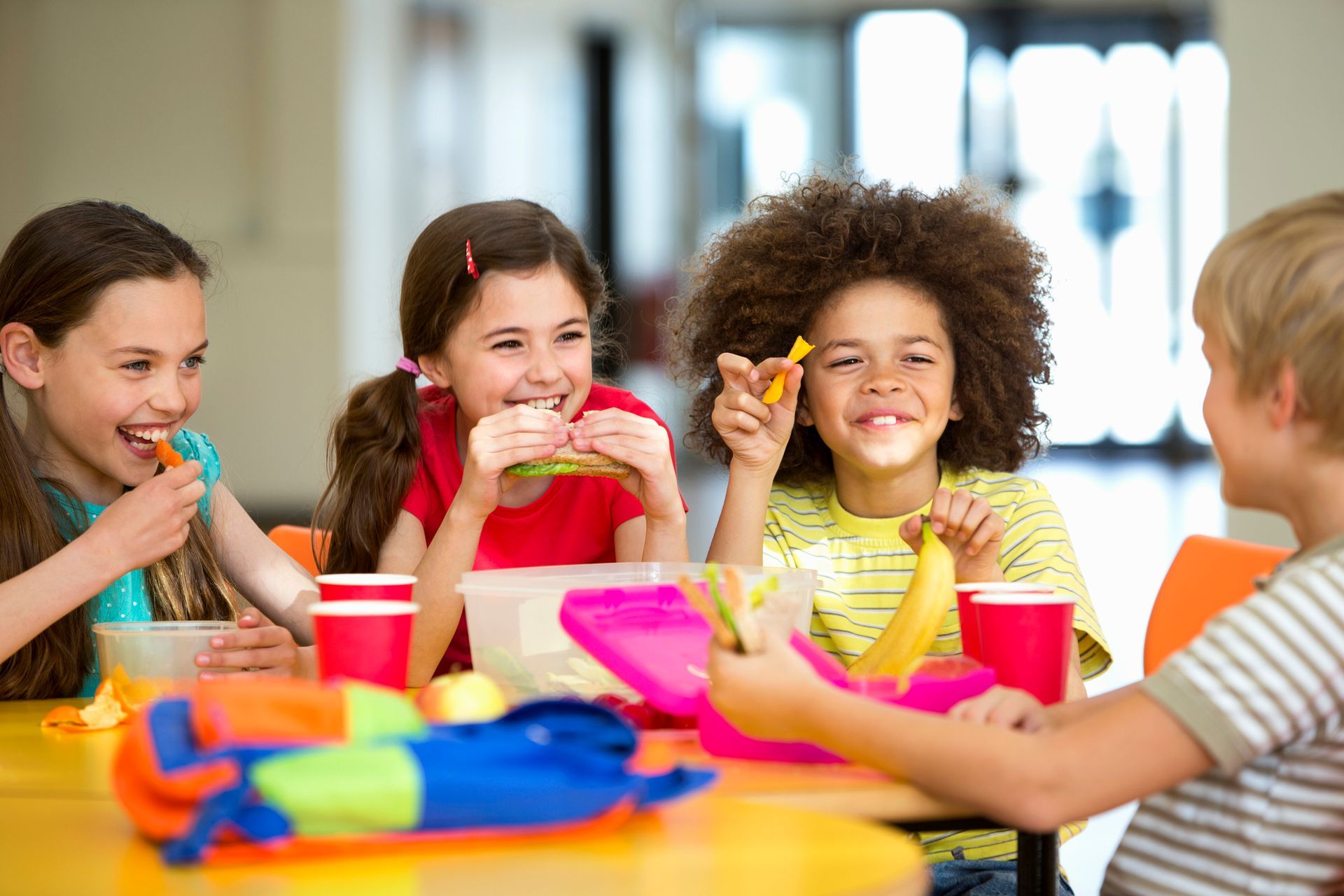 A group of children are sitting at a table eating food.