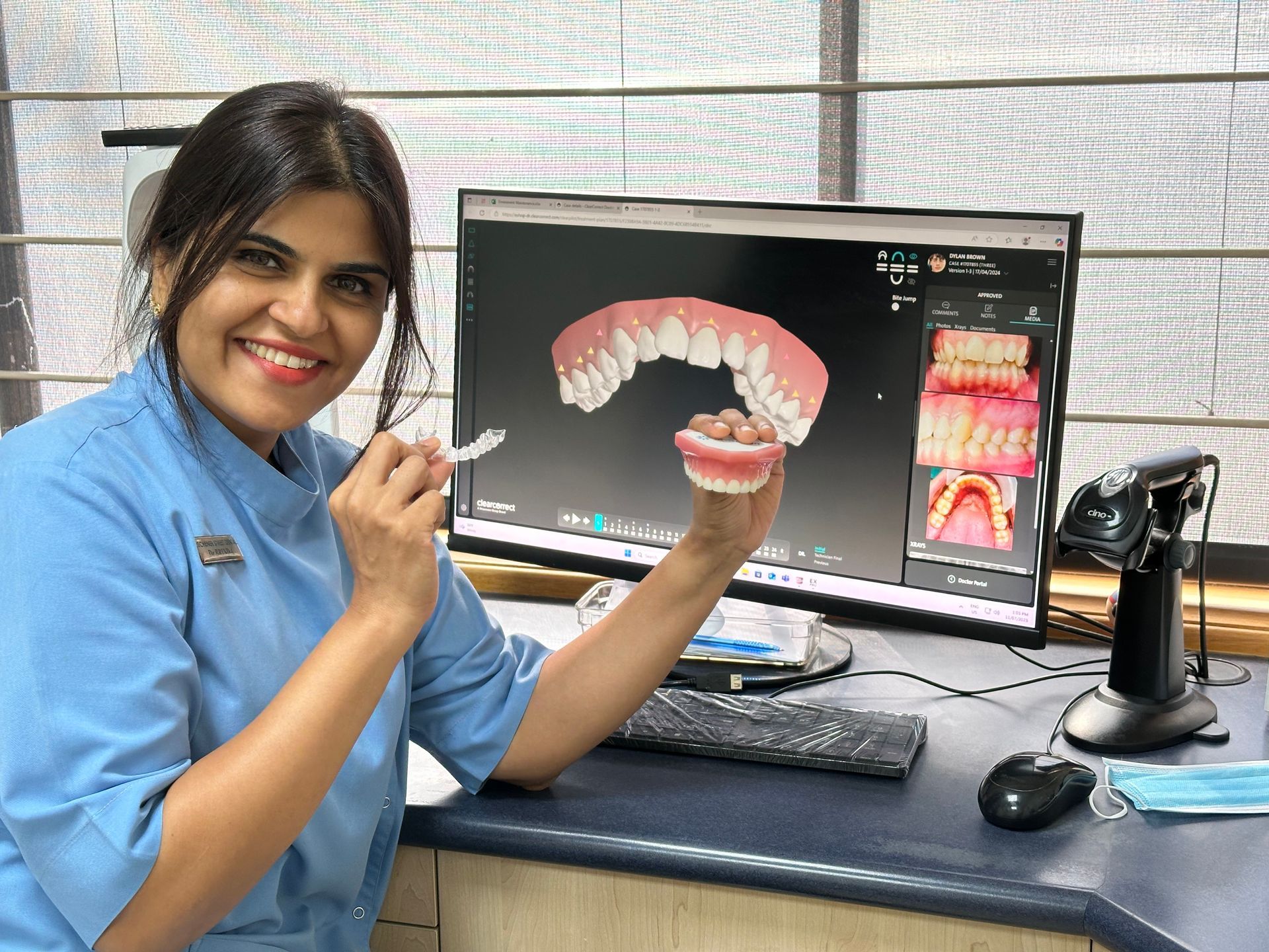 A woman is holding a model of teeth with braces and a pen.