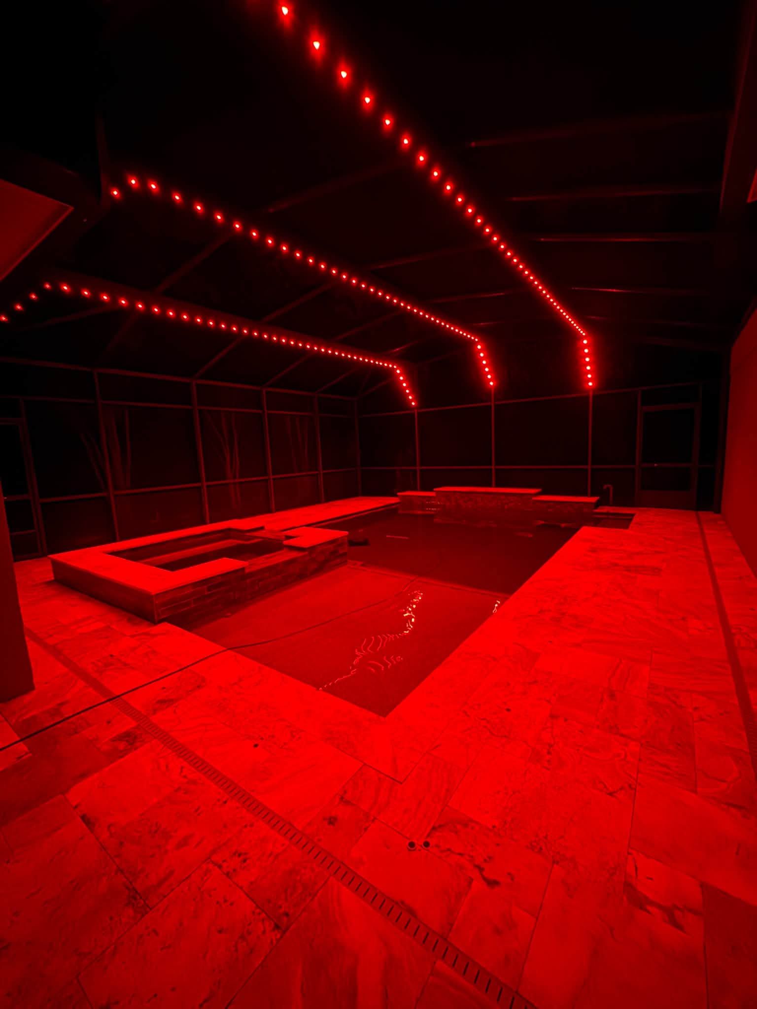 Red-lit empty lounge with angular couches and rows of ceiling lights