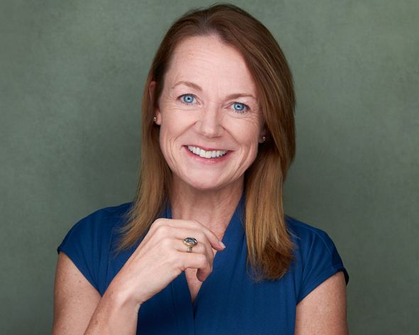 Smiling woman in a blue top against a muted green background