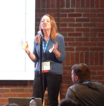 Amy Hooper Hanna speaking at a keynote, gesturing with both hands