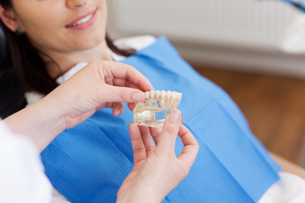 A Woman is Sitting in a Dental Chair — Dental Prosthetics By Richard & Cindy in Oxenford, QLD