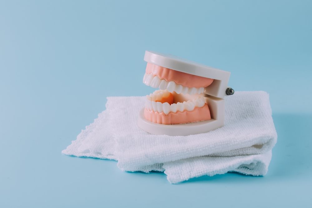 A Model of Teeth is Sitting on a White Towel on a Blue Background — Dental Prosthetics By Richard & Cindy In Oxenford, QLD