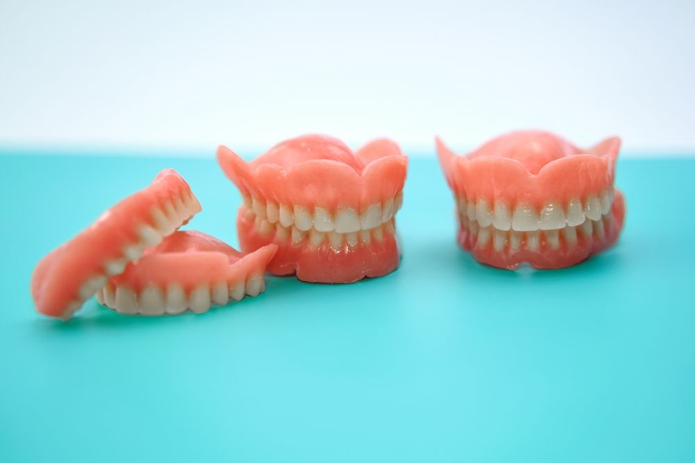 Three Dentures Are Sitting on a Blue Table — Dental Prosthetics By Richard & Cindy In Oxenford, QLD