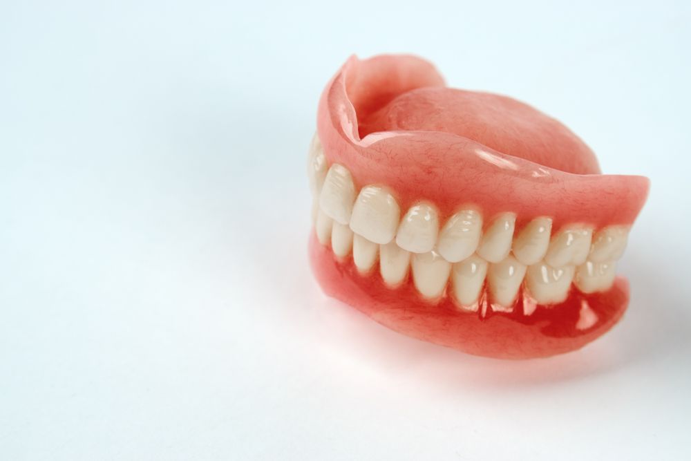 Full set of dentures with natural-looking teeth displayed on a clean white background studio setup.