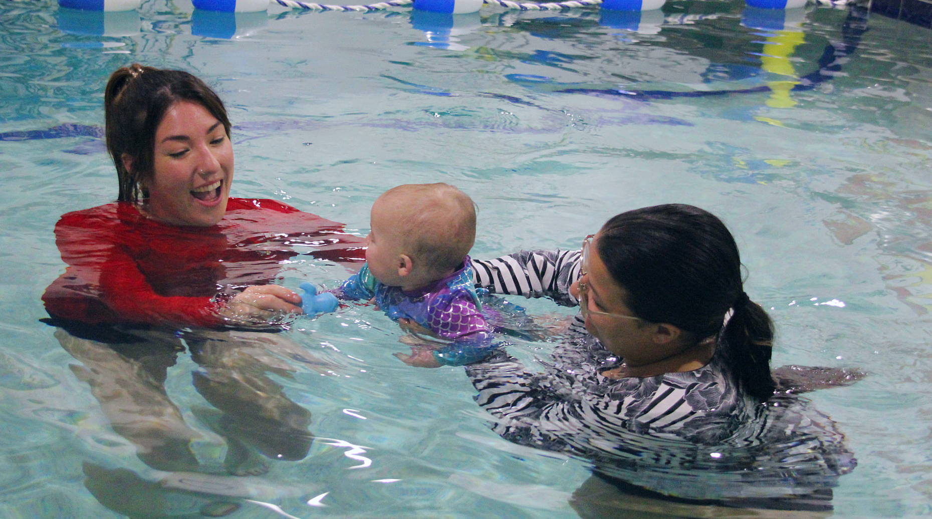 Swimming Instructor teaching a little girl how to swim in a swimming pool.