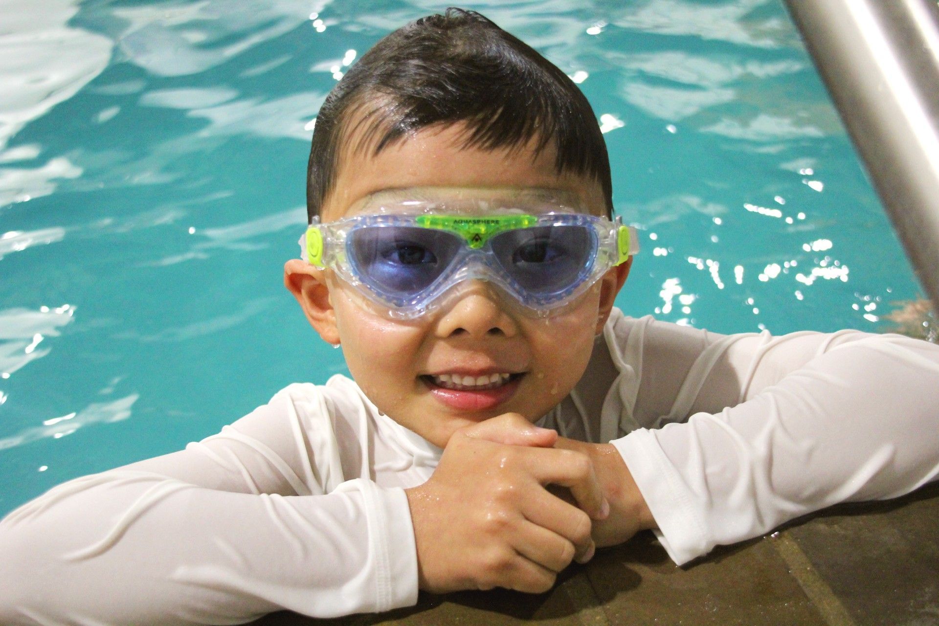 Swimming lessons a woman is teaching a young boy how to swim in a pool.