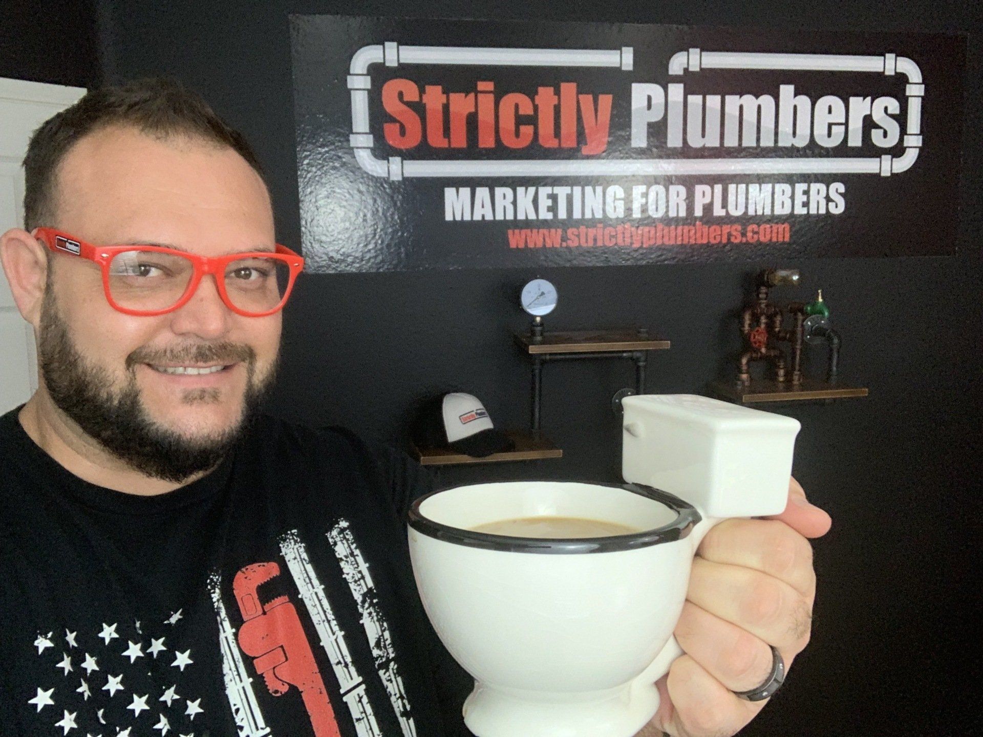 A man holding a cup of coffee in front of a sign that says strictly plumbers