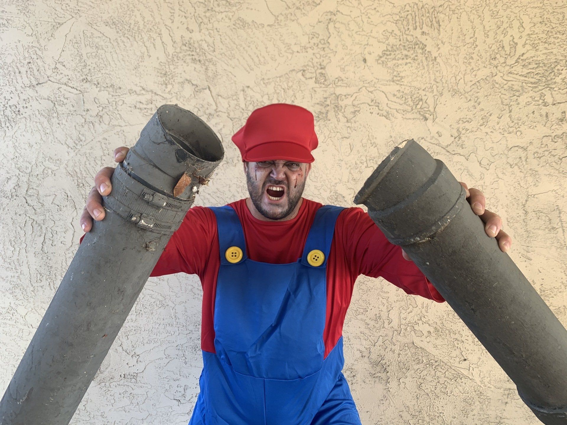A man dressed as mario is holding two pipes in his hands