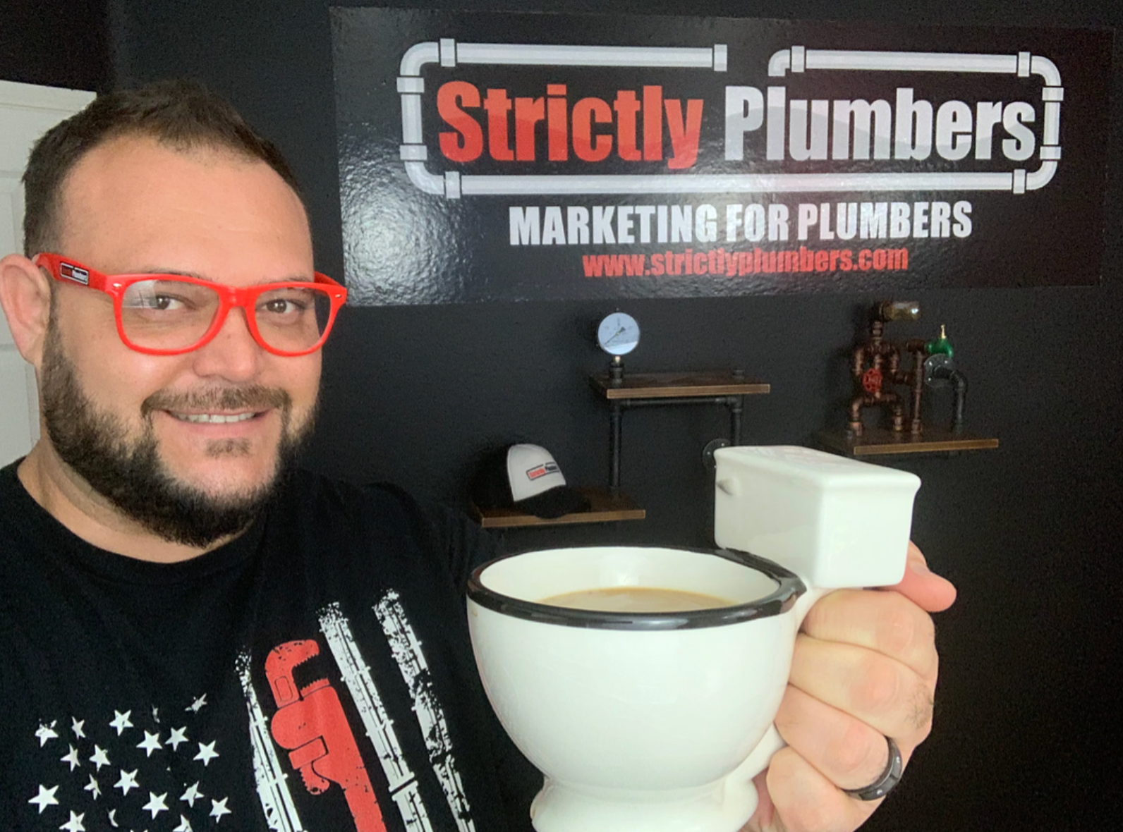 A man holding a cup of coffee in front of a sign that says strictly plumbers