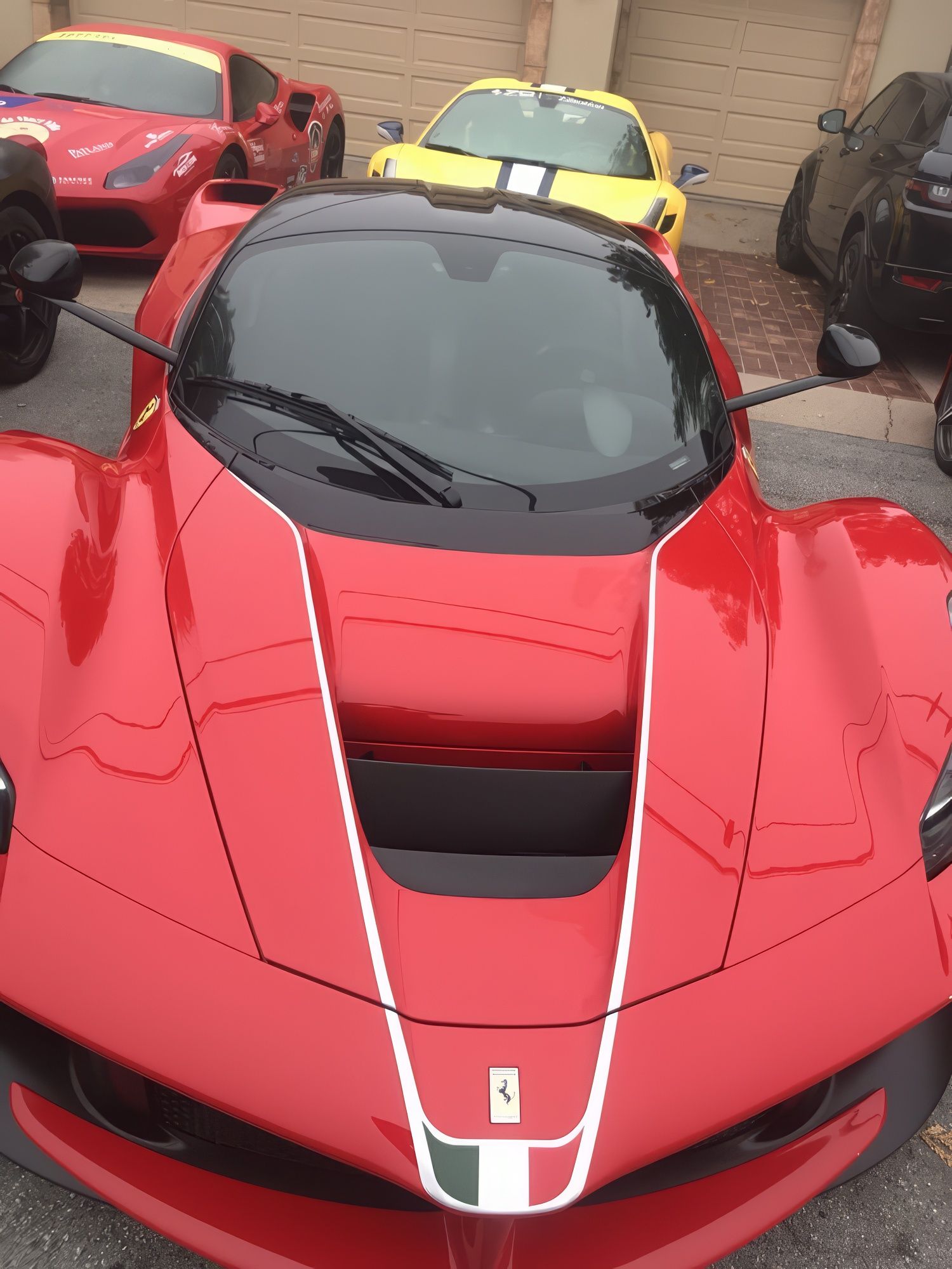 Red Ferrari sports car parked in front, with yellow and black cars behind it.