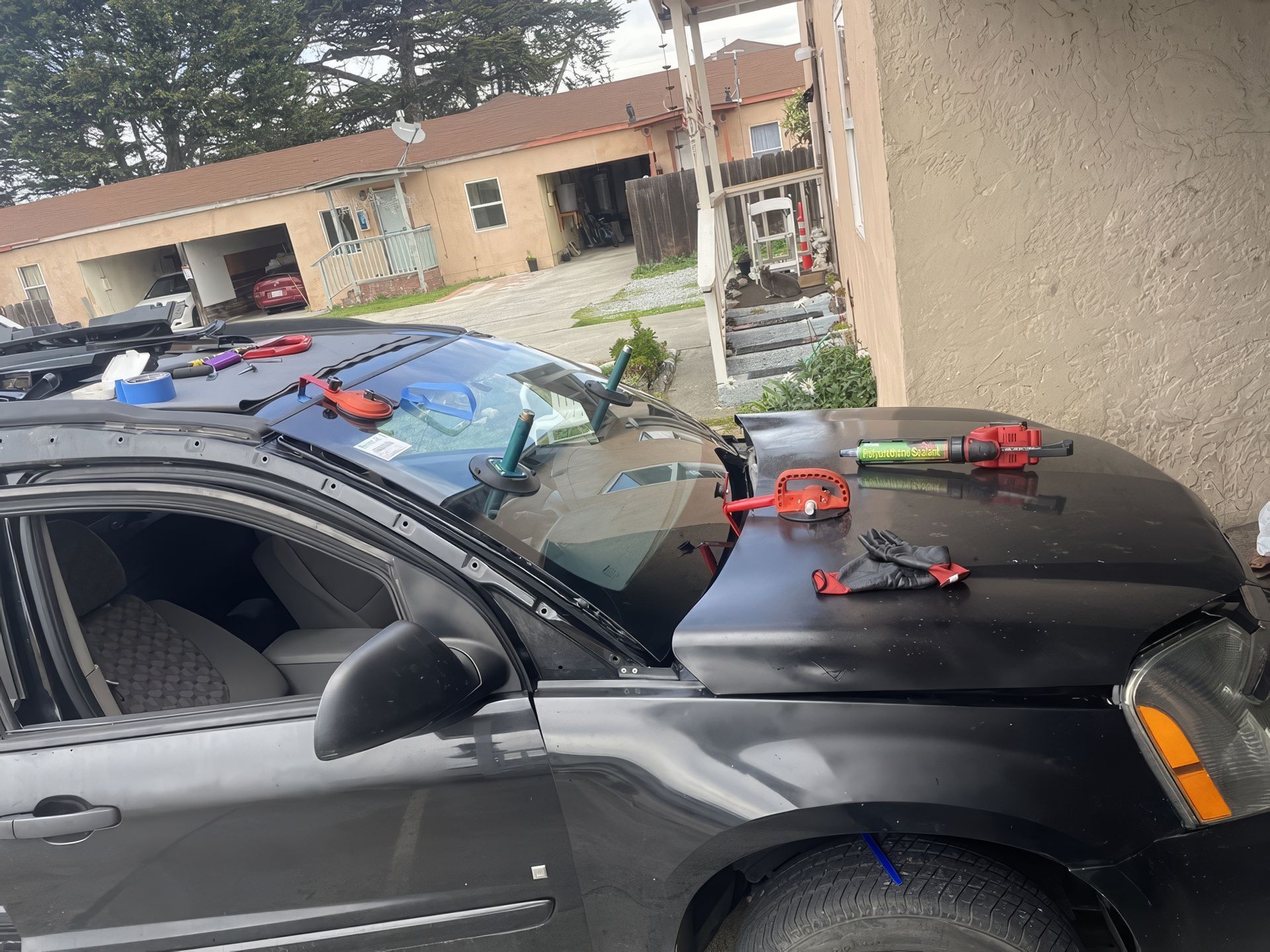 Black SUV with several toy blasters taped to the hood and roof in a residential driveway