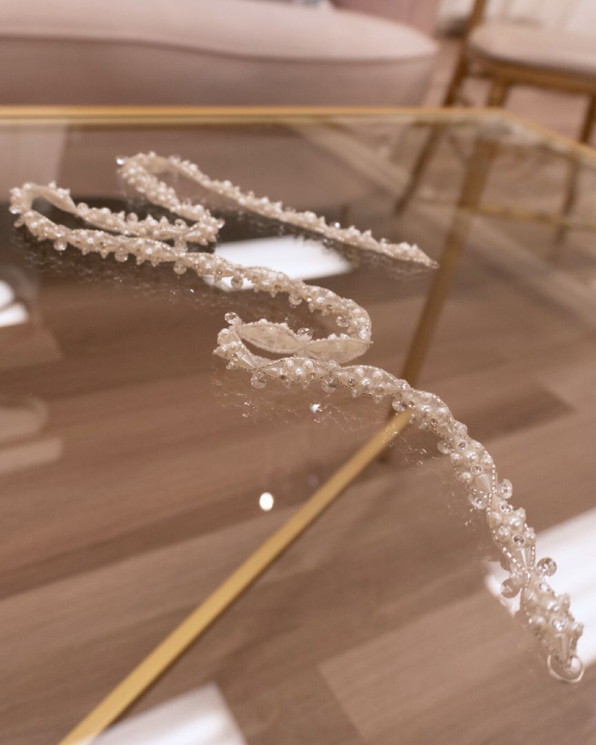 Beaded, swirling decoration on a thin, golden stick, resting on a glass table.