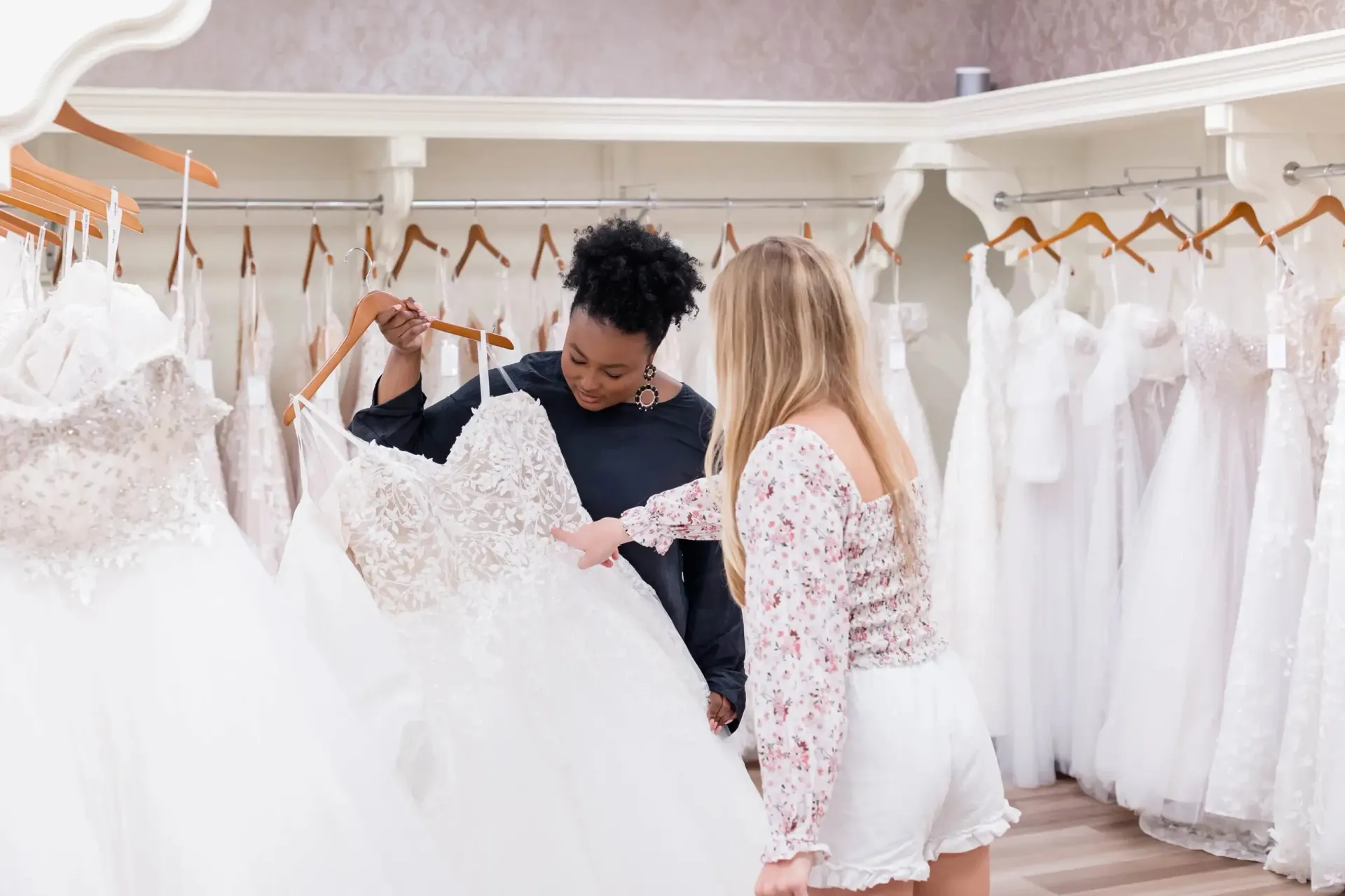 Two people looking at a wedding dress in a bridal shop.