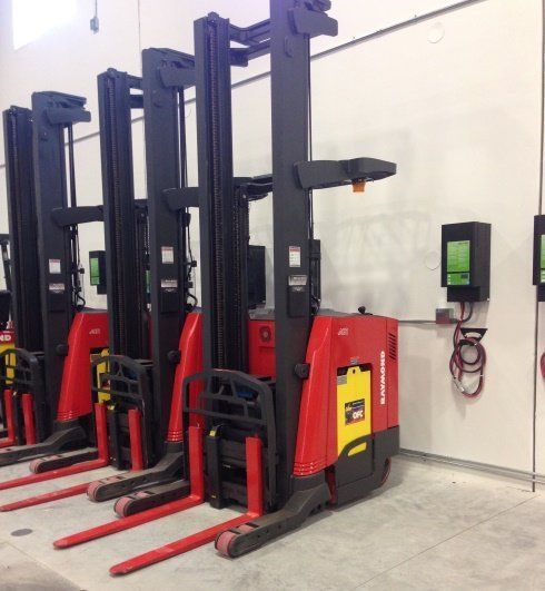 A row of forklifts are lined up in a warehouse