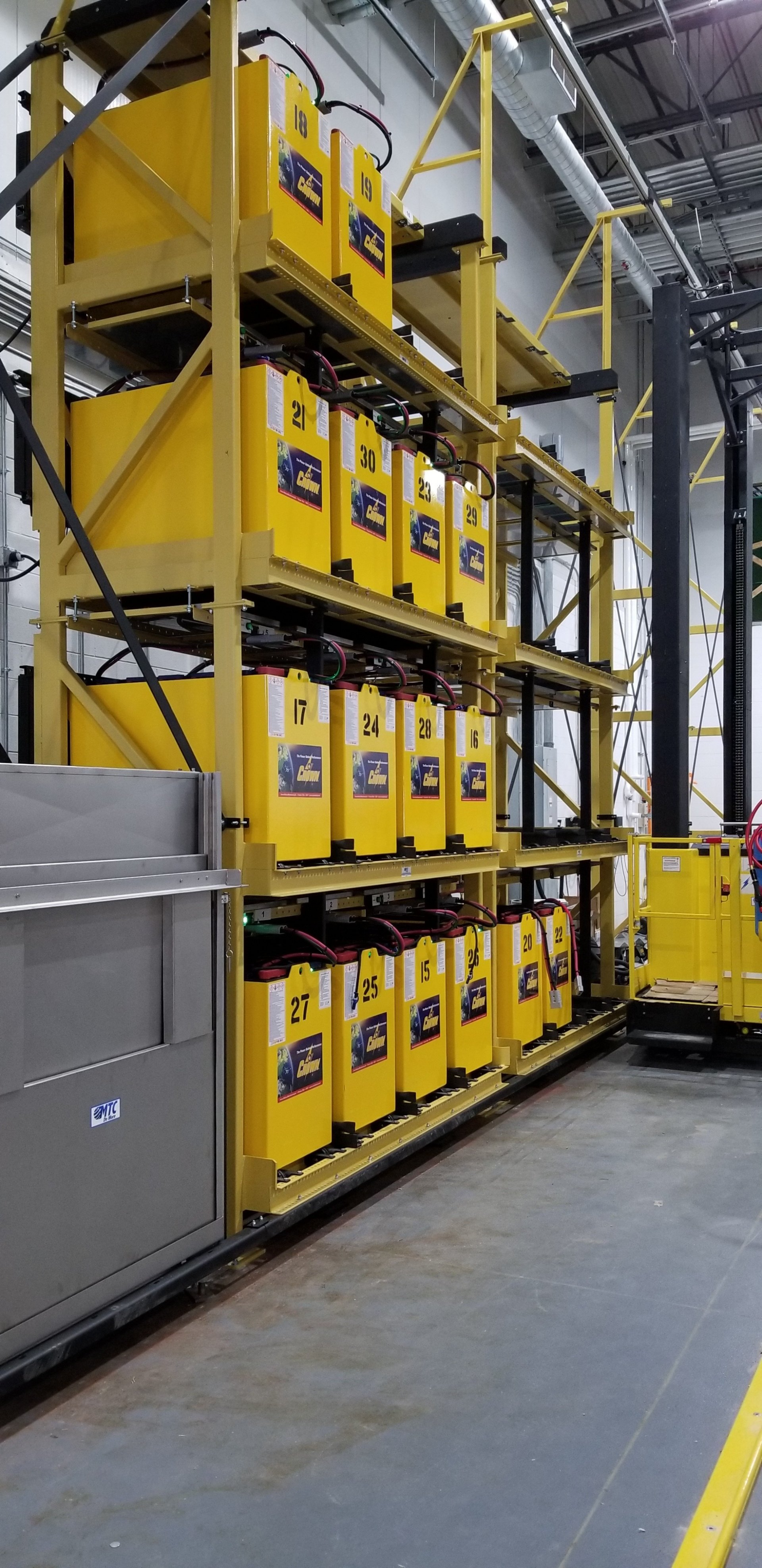 A warehouse filled with lots of yellow batteries and a forklift.
