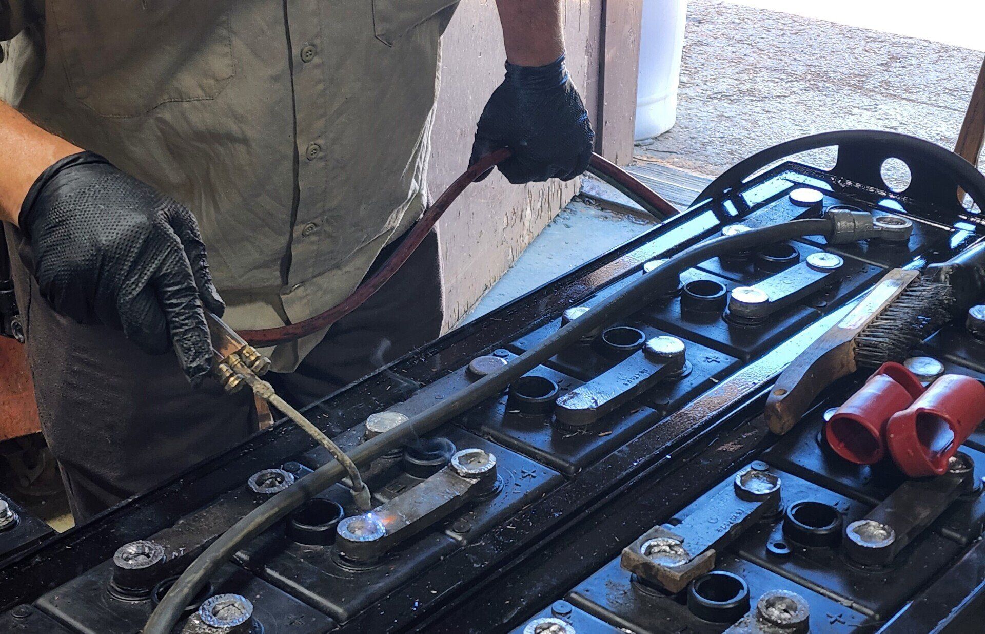 A man is working on a battery with a welding torch.