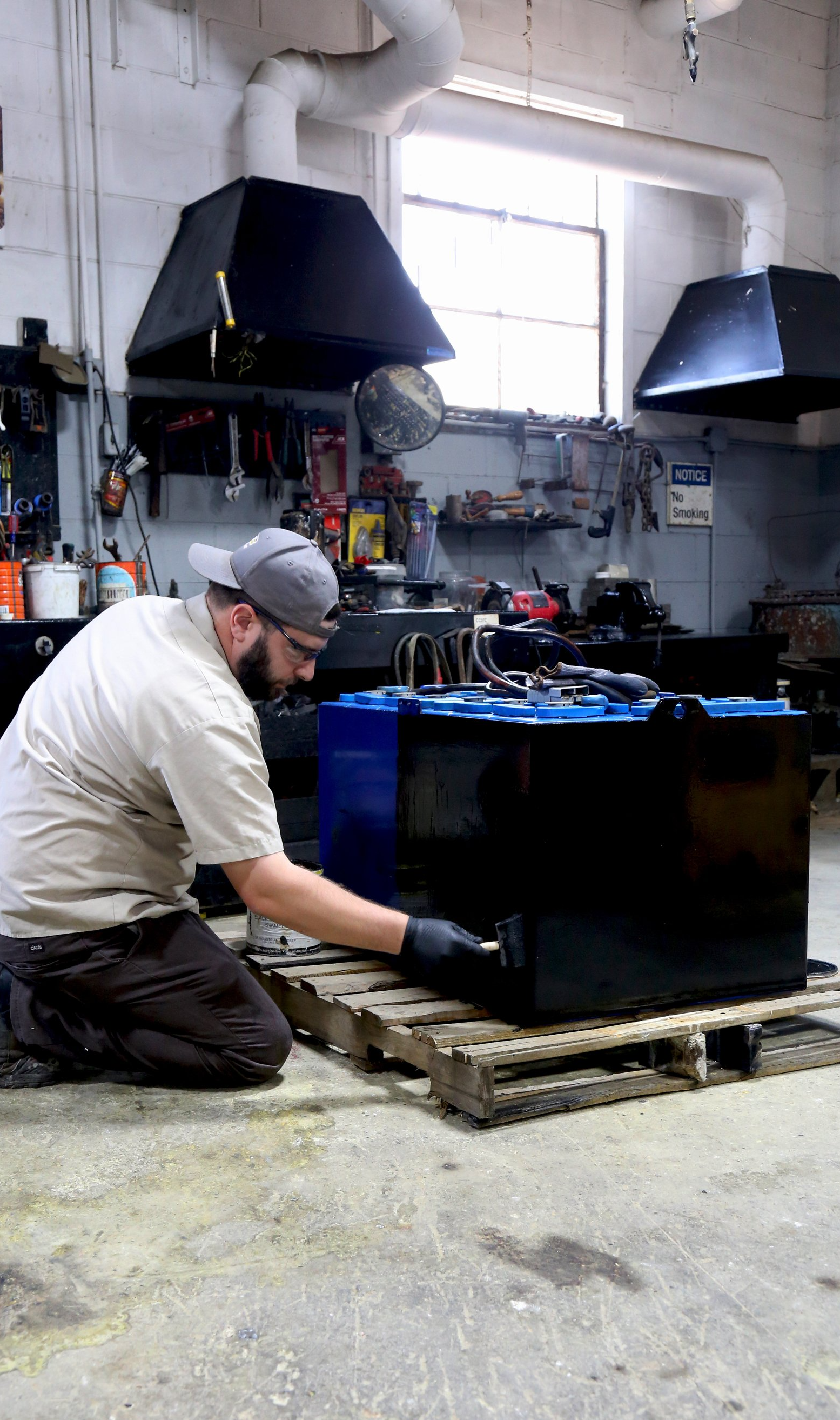 A man is working on a battery in a garage.