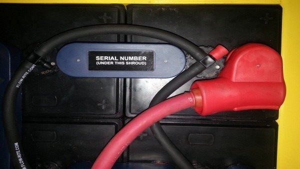 A close up of a battery with a red cable attached to it