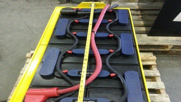 A battery is being measured with a tape measure