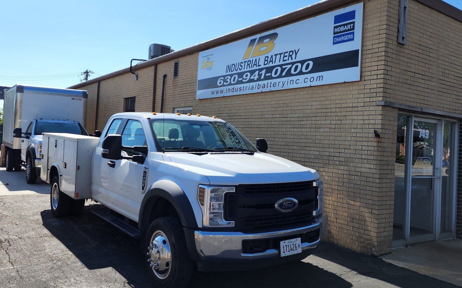 A white truck is parked in front of a brick building.
