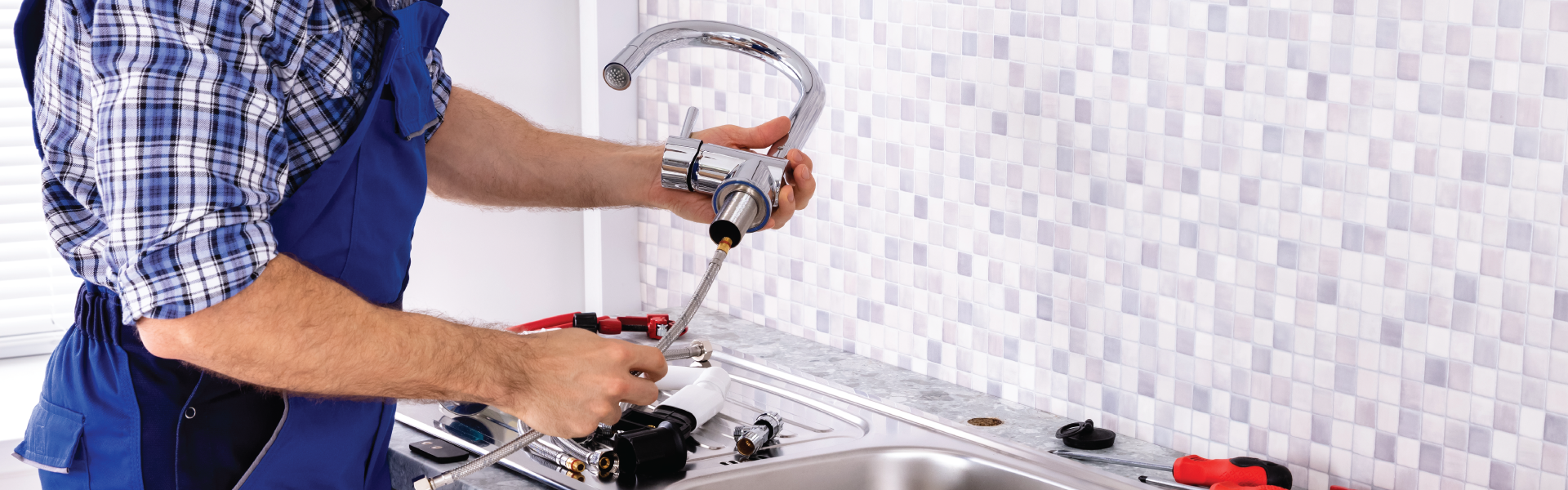 A plumber is fixing a sink faucet with a screwdriver.