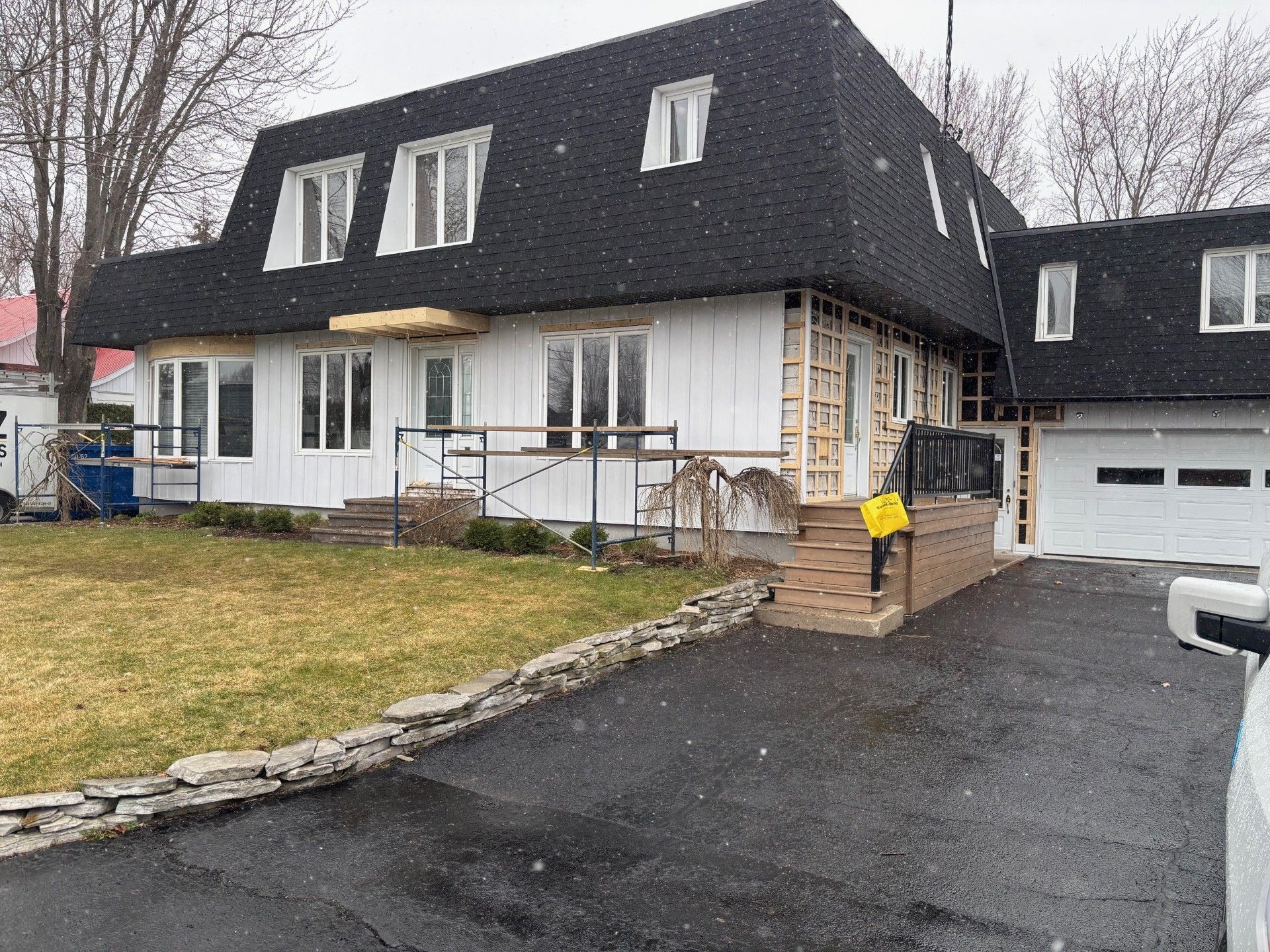 Une grande maison blanche avec un toit noir est en cours de rénovation.