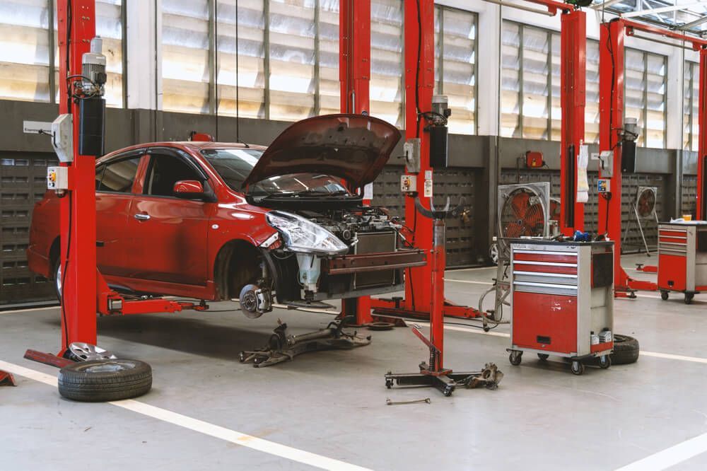 A Red Car is Sitting on a Lift in a Garage — Reliable Bus and Truck Repairs In Caloundra West, QLD