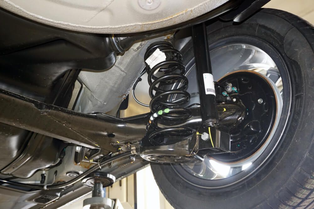 The Underside of a Car With a Shock Absorber and a Tire — Reliable Bus and Truck Repairs In Caloundra West, QLD