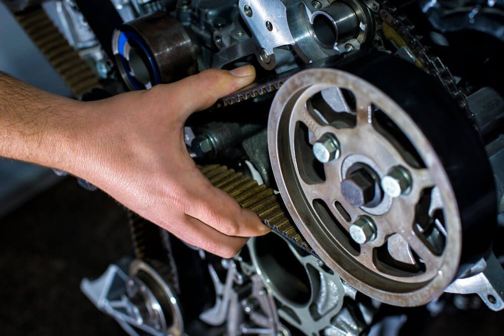 A Person is Fixing a Belt on a Car Engine — Reliable Bus and Truck Repairs in Caloundra West, QLD