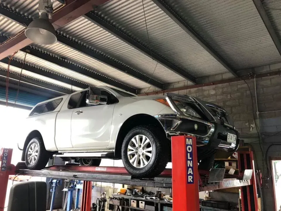 A White Truck is on a Lift in a Garage — Reliable Bus and Truck Repairs In Caloundra West, QLD