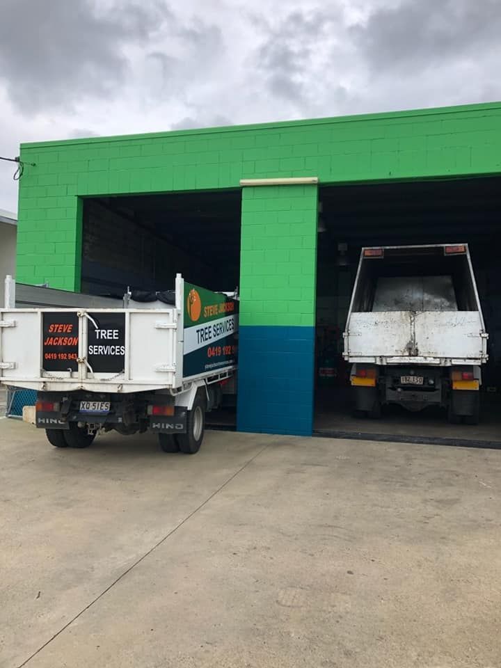 Two Trucks Are Parked in Front of a Green Building — Reliable Bus and Truck Repairs In Caloundra West, QLD