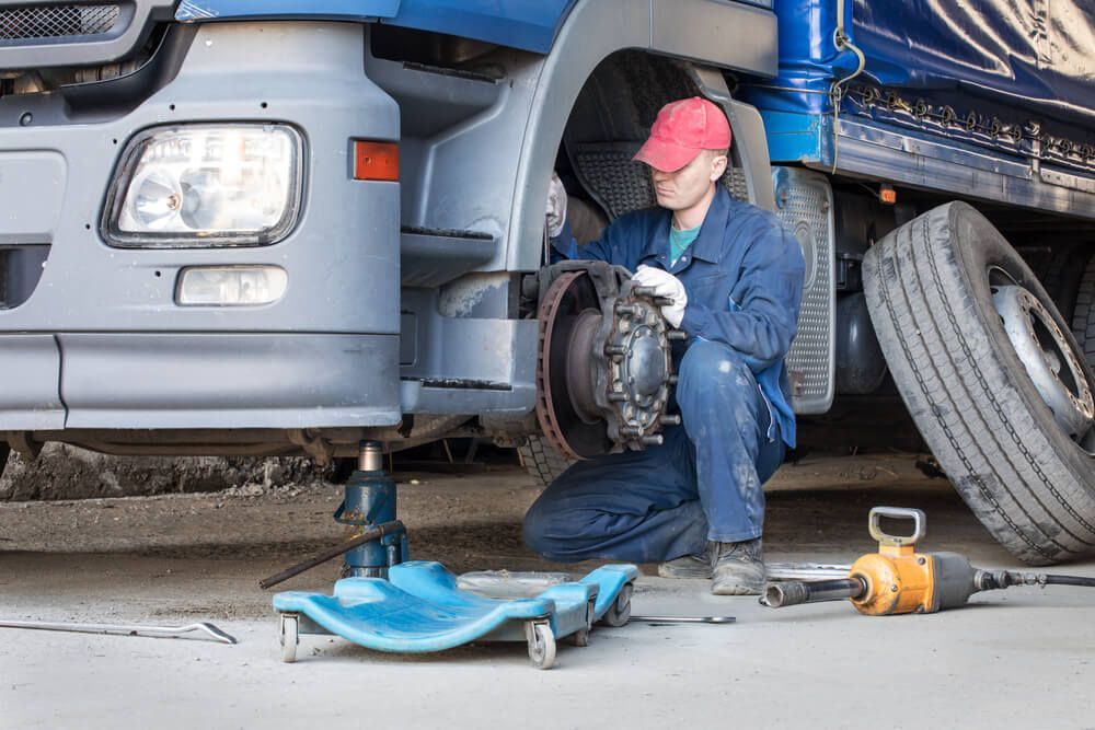 A Man is Working on a Truck in a Garage — Reliable Bus and Truck Repairs In Caloundra West, QLD
