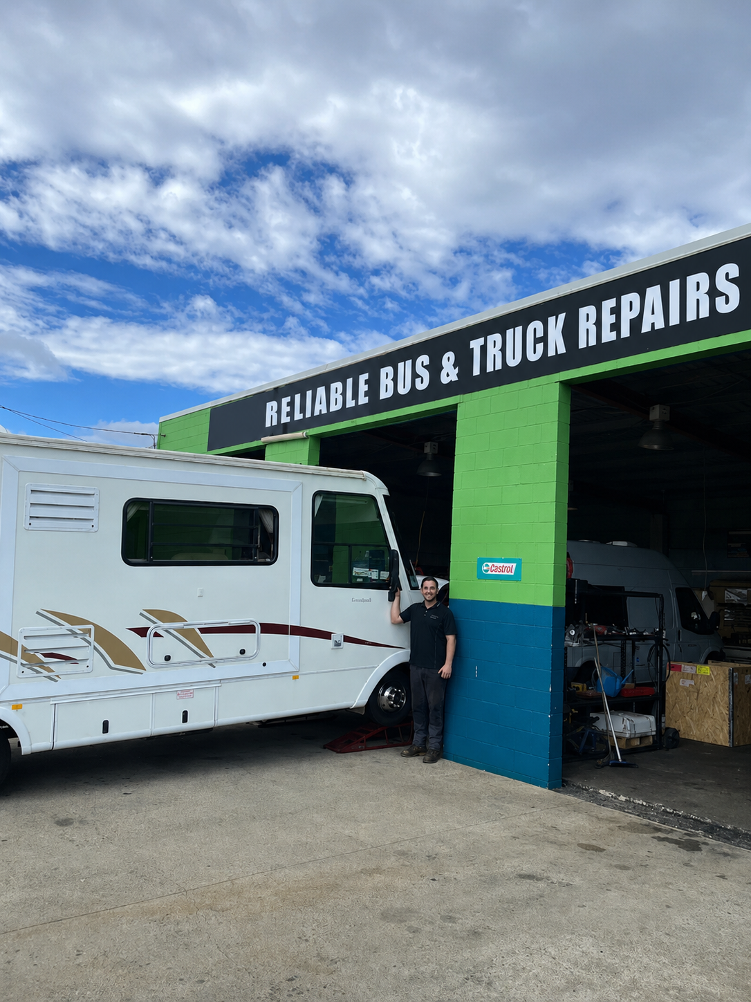 White RV Outside Green-and-blue Reliable Bus & Truck Repairs Garage — Reliable Bus and Truck Repairs In Caloundra West, QLD