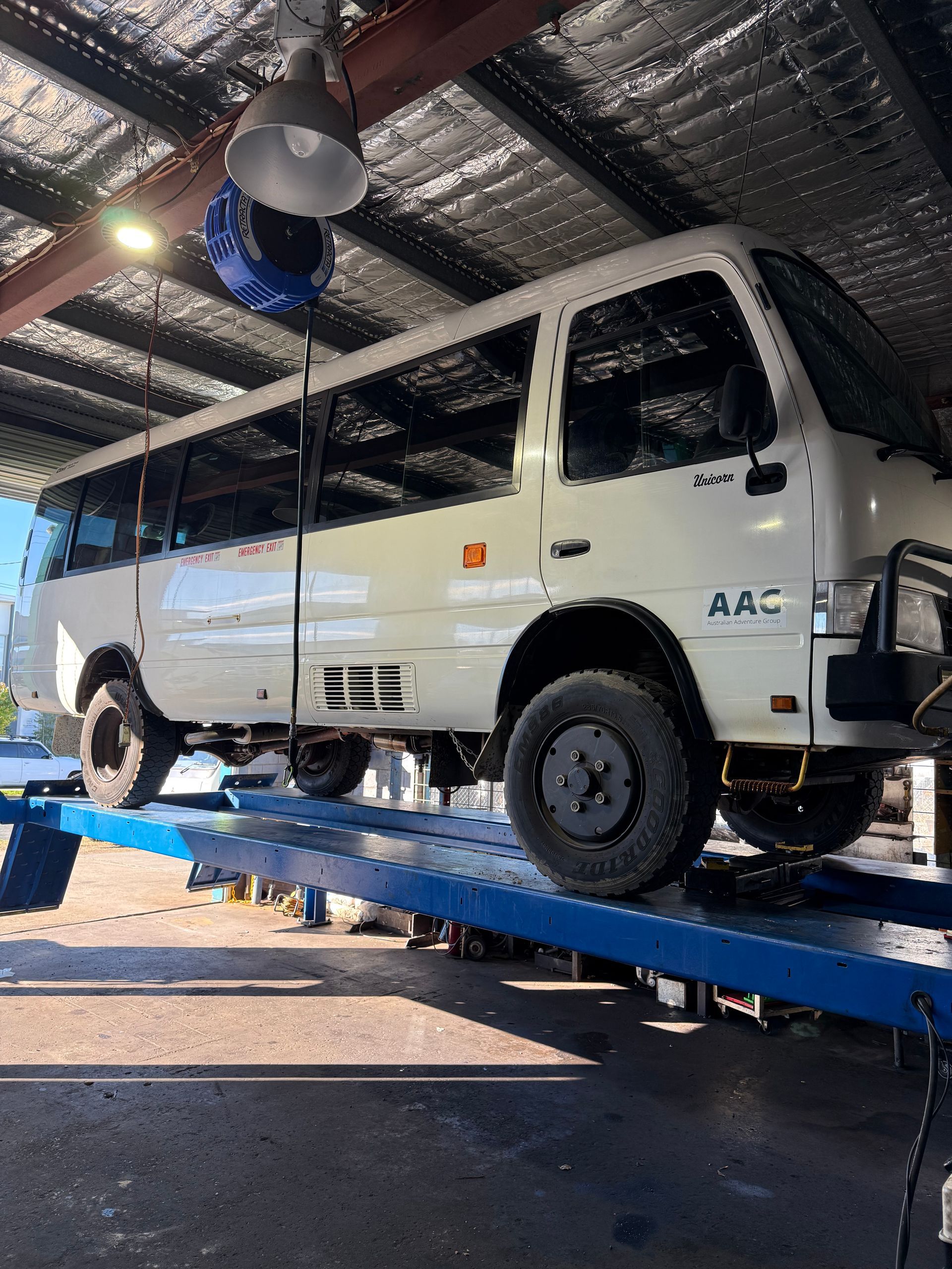 White Pickup Truck on a Blue Car Lift Inside an Auto Shop — Reliable Bus and Truck Repairs In Caloundra West, QLD