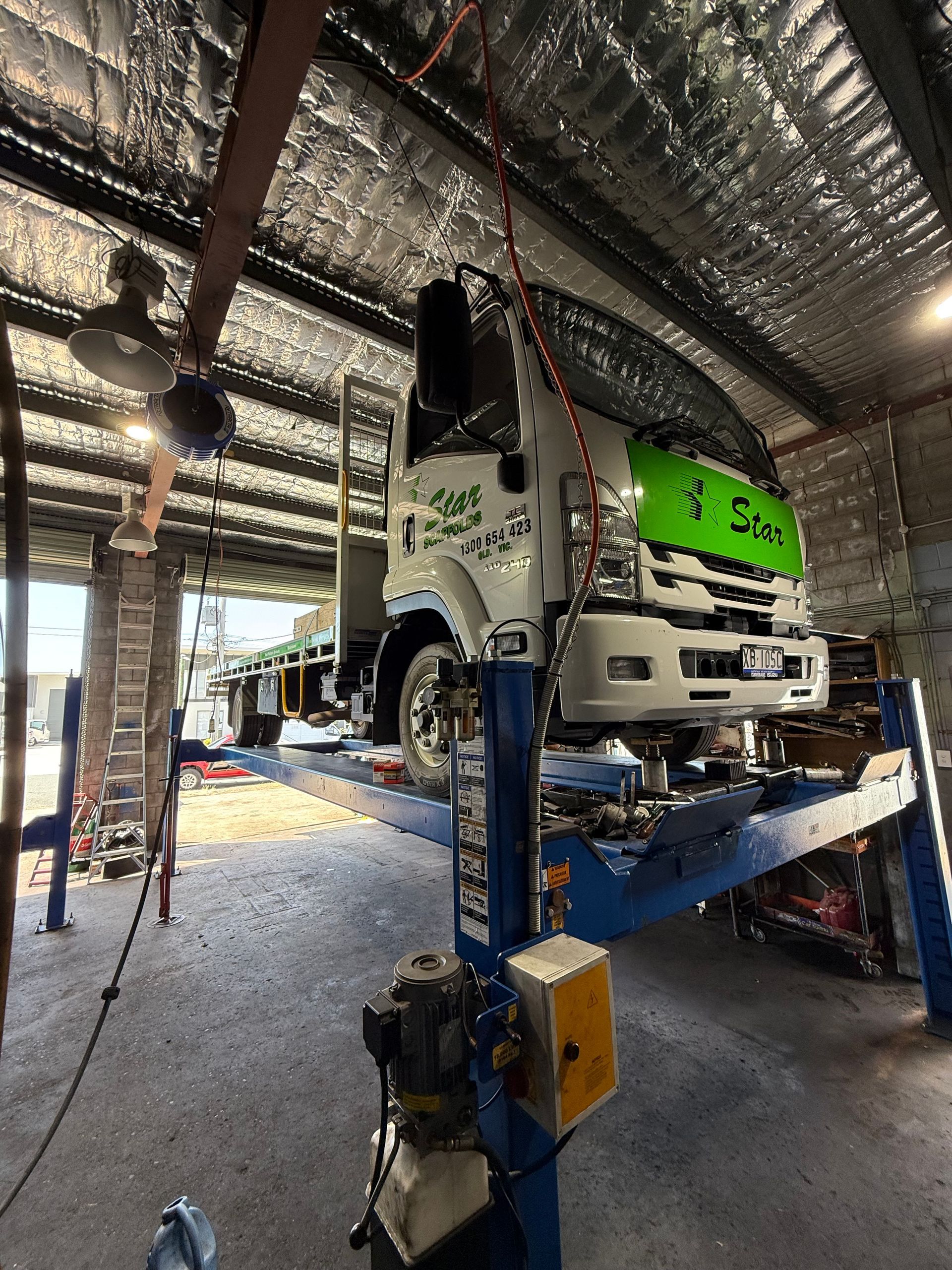 Truck On a Blue Hydraulic Lift Inside a Garage — Reliable Bus and Truck Repairs In Caloundra West, QLD
