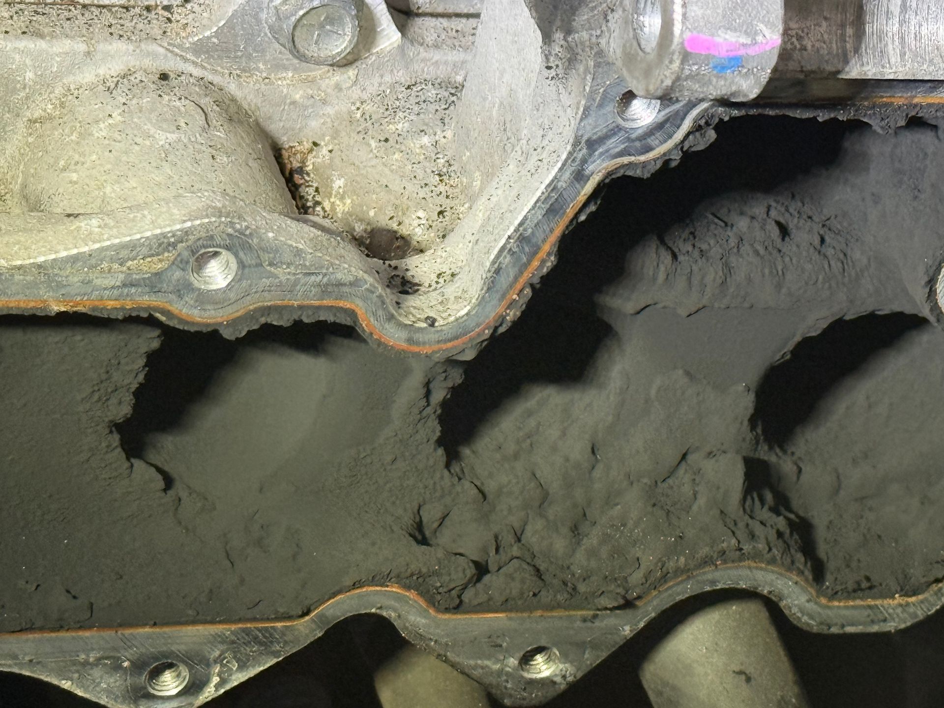 Close-up of a Damaged Metal Engine Gasket With Dark Sludge Buildup — Reliable Bus and Truck Repairs In Caloundra West, QLD