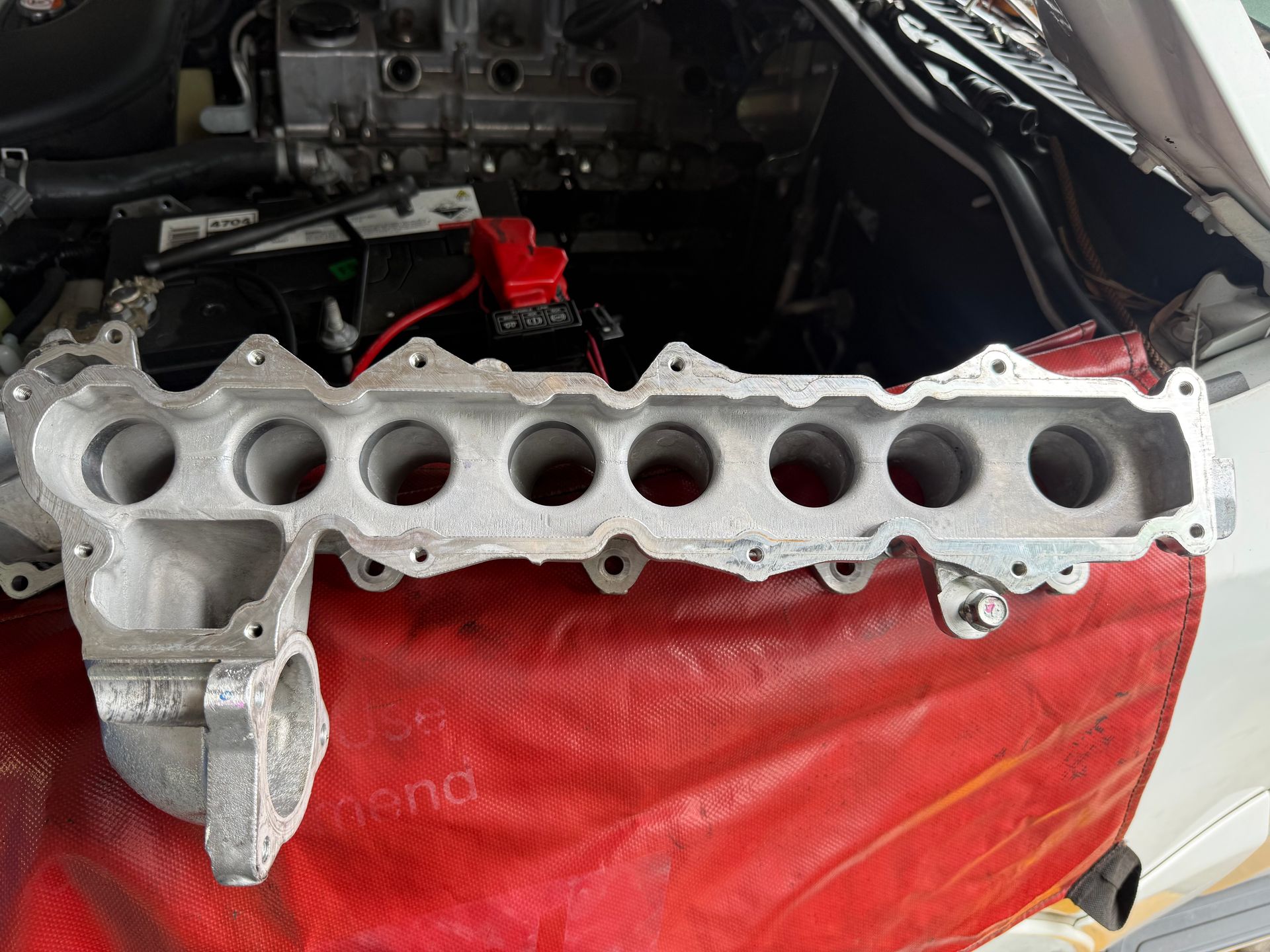 Car Engine Cylinder Head on a Red Fender Cover — Reliable Bus and Truck Repairs In Caloundra West, QLD